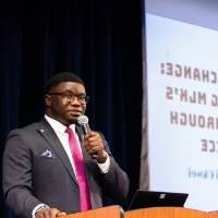 Albert Okwei with microphone at podium